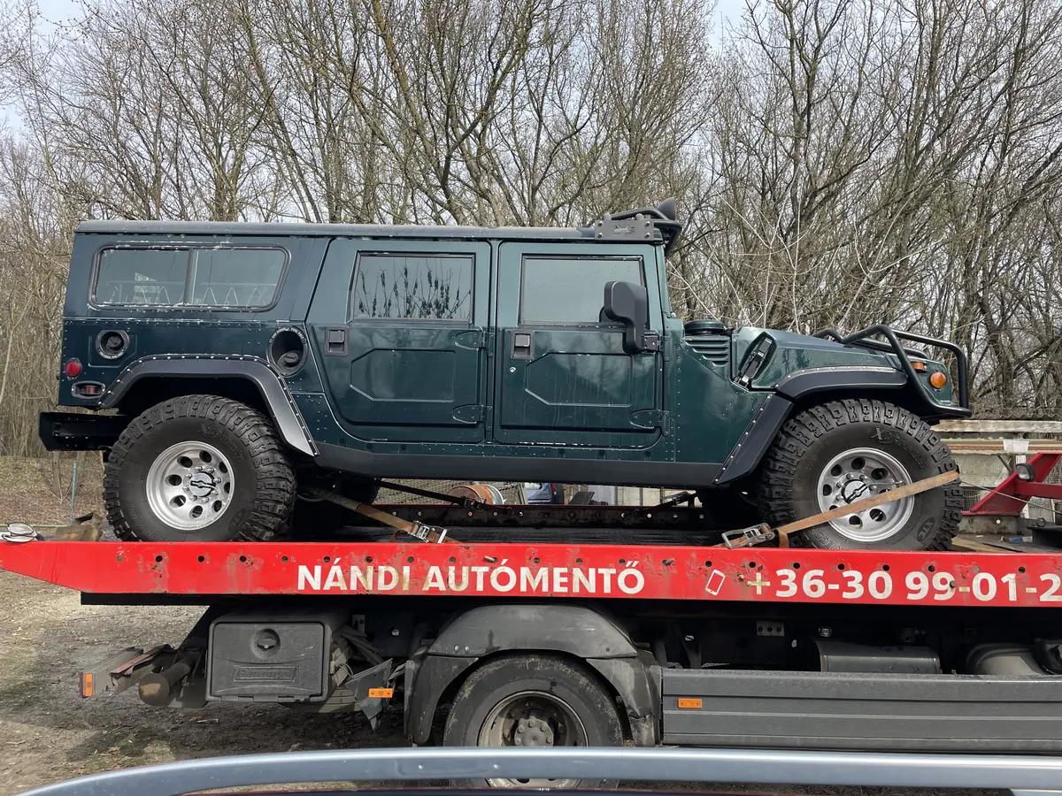 Sötétzöld Hummer H1 Nándi trélerén, a platón a Nándi autómentő felirat